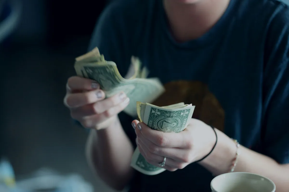 Person counting cash while reviewing their monthly spending.